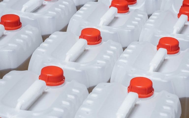 Descripción: Una fila de jarras de plástico con tapas naranjas para la gestión de residuos.