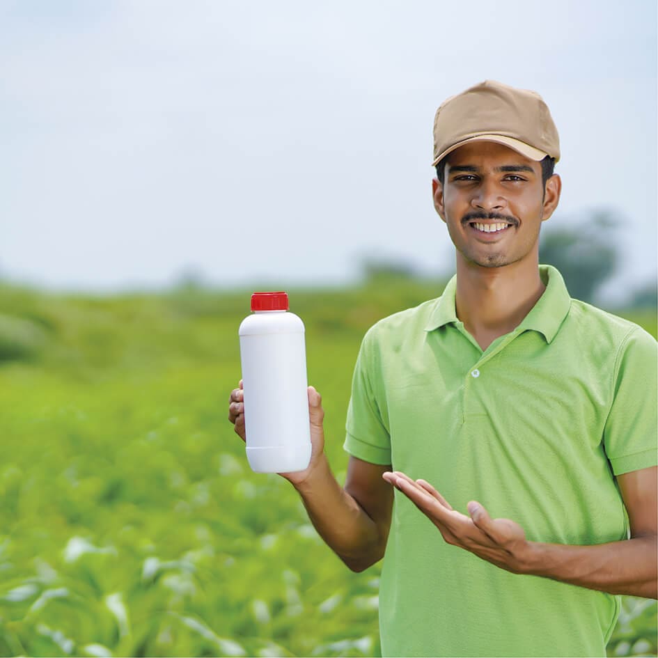 Un hombre sosteniendo una botella de fertilizante en un campo.